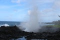 A blowhole spraying water high into the air onto volcanic rock at Waianapanapa State Park, Hana, Maui Royalty Free Stock Photo
