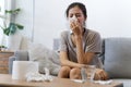 Sick Asian young woman sneeze at home on the sofa with a cold. Royalty Free Stock Photo