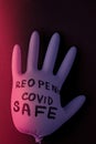 Blown up blue latex surgical glove on black background. Reopening covid safe. Open again text written on medical glove