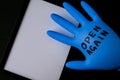 Blown up blue latex surgical glove on black background. Reopening covid safe. Open again text written on medical glove