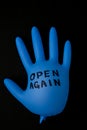 Blown up blue latex surgical glove on black background. Reopening covid safe. Open again text written on medical glove
