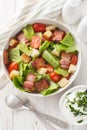 BLT salad is loaded with fresh lettuce, crispy bacon, bright tomatoes croutons closeup on the plate. Vertical top view