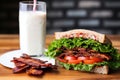 blt sandwich next to a tall glass of milk