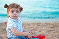 Blu eyes brunette toddler girl playing with sand in beach Royalty Free Stock Photo