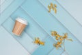 On a blue, abstract background, dry yellow flowers and a paper cup from under the coffee. Nice layout, there is a place for text. Royalty Free Stock Photo