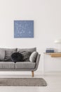 Blue abstract painting on white wall of fashionable living room interior with grey couch and console table Royalty Free Stock Photo