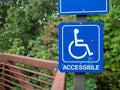 Blue accessible handicap sign hanging on nature hiking path