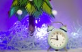 blue alarm clock against the background of a green Christmas tree, the new year is coming soon. 2023 Royalty Free Stock Photo