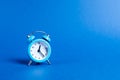 A blue alarm clock on a blue background. Limited offer and over time. Planning and discipline. waiting for a meeting. Punctuality