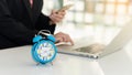 The blue alarm clock on the business man`s desk is working Royalty Free Stock Photo