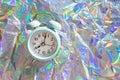 Blue alarm clock on crumpled holographic shiny background with copy space