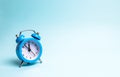 A blue alarm clock on a light blue background. The concept of waiting for a meeting, a date. Punctuality. The cost of hourly work