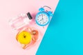 Blue alarm clock with oatmeal, apple and measuring tape on a pink and blue background. Healthy nutrition concept. Top views with Royalty Free Stock Photo