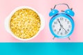 Blue alarm clock with oatmeal on a pink and blue background. Healthy nutrition concept. Top views with clear space