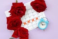 Blue alarm clock and red rose flowers on menstrual period calendar with red cross marks Royalty Free Stock Photo