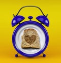 Blue alarm clock with toast bread heart concept isolated on yellow background Royalty Free Stock Photo