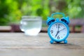 Blue alarm clock on wooden with green blurred back Royalty Free Stock Photo