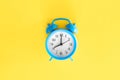 Blue alarm clock on a yellow background, top view.
