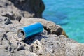 blue aluminum beverage can left behind on stone coast on mediterriean, problem of marine pollution