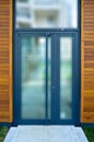 Blue aluminum framed entrance door of a modern office building, walls are tiled with mahogany wood