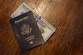 Blue American passport with some US dollars on top of a wooden desk