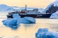 Blue antarctic cruise vessel among the icebergs with glacier in