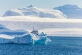 Blue antarctic cruise vessel among the icebergs with glacier in Royalty Free Stock Photo