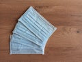 Blue antiviral surgical protective face masks stacked together on a wooden table.