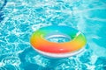 Blue aqua background. Pool float, rainbow ring floating in a refreshing blue swimming pool. Inflatable ring floating in Royalty Free Stock Photo