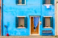 Blue aqua colored house with flowers and bench. Colorful houses in Burano island near Venice, Italy. Venice postcard. Famous place