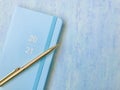 Blue new diary with golden 2021 words, golden pen, blue background. close up.