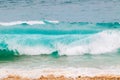 Blue and aquamarine color sea waves and yellow sand  with white foam. Marine beach background. Royalty Free Stock Photo