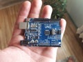 Blue Arduino Uno board electronics in hand for programming the microcontroller