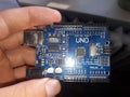 Blue Arduino Uno board electronics in hand for programming the microcontroller