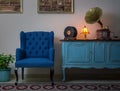 Blue armchair, vintage wooden light blue sideboard, lighted antique table lamp, old phonograph gramophone and vinyl records