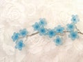 Cute beautiful blue artificial flowers on the white lace background Royalty Free Stock Photo
