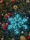 A blue artificial snowflake and Christmas balls of various colors, both gold and silver and red, hang on the branches of a. Royalty Free Stock Photo