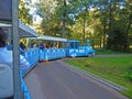 A blue attraction train carrying tourists through a park