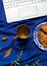 Blue autumn business flat lay with laptop, fall leaves, croissants and cup of tea for breakfast. Work from home concept Royalty Free Stock Photo