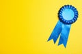 Blue award ribbon on yellow background, top view. Space for text Royalty Free Stock Photo
