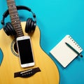 Blue backdrop, acoustic guitar with headphones, smartphone, and notebook , close up, technology Royalty Free Stock Photo