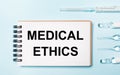 On a blue background ampoule with medicines and a notebook with the text MEDICAL ETHICS. Medical concept Royalty Free Stock Photo