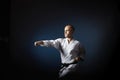 On a blue background with a gradient, an athlete with a black belt does formal karate exercises.