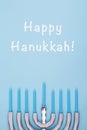 Blue background with menora and candles and Happy Hanukkah wording. Hanukkah and judaic holiday concept.