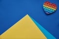 On blue background, multi-colored silicone anti-stress toy in tshape of heart and a pyramid, mountain of yellow-blue