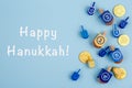 Blue background with multicolor dreidels and chocolate coins and Happy Hanukkah wording. Hanukkah and judaic holiday Royalty Free Stock Photo