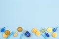 Blue background with multicolor dreidels, menora candles and chocolate coins. Hanukkah and judaic holiday concept.