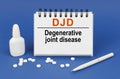 On a blue background, a pen, tablets and a notepad with the inscription - DJD Degenerative joint disease Royalty Free Stock Photo