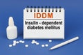 On a blue background, a pen, tablets and a notepad with the inscription - IDDM Insulin-dependent diabetes mellitus