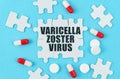 On a blue background, pills, capsules and puzzles with the inscription - Varicella zoster virus